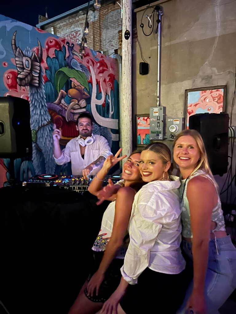 DJ EnSueño performing at an intimate venue with vibrant street art